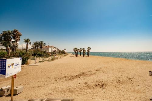 a sandy beach with palm trees and the ocean at encantador apto en la playa in Comarruga