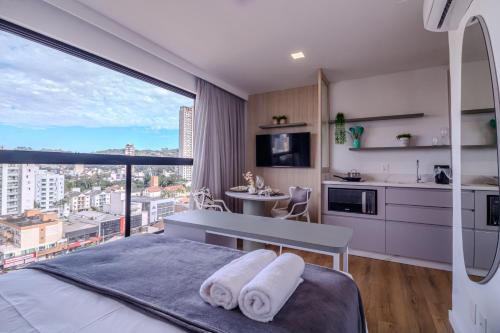 a bedroom with a view of a kitchen and a bed at Loft Novo todo Mobiliado com WIFI Piscina e próximo a Oktober in Blumenau