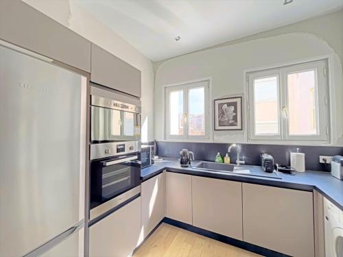 une cuisine avec des armoires blanches et un four à plaques de cuisson dans l'établissement IRIS APARTMENT backCroisette, à Cannes