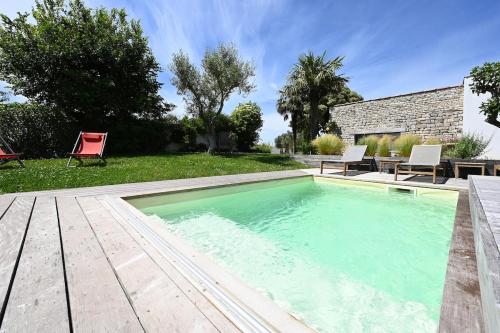 une piscine dans une cour arrière avec une table et des chaises dans l'établissement 999 Le Moulin - Pool and nature, à La Couarde-sur-Mer