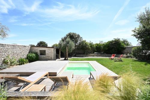 une cour arrière avec une piscine et une terrasse en bois dans l'établissement 999 Le Moulin - Pool and nature, à La Couarde-sur-Mer