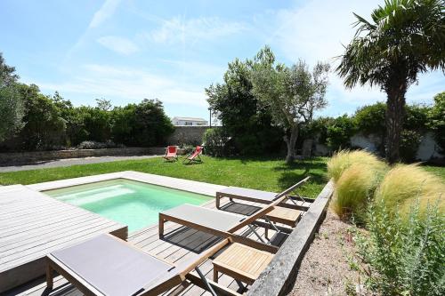 une piscine avec deux chaises et une table dans l'établissement 999 Le Moulin - Pool and nature, à La Couarde-sur-Mer