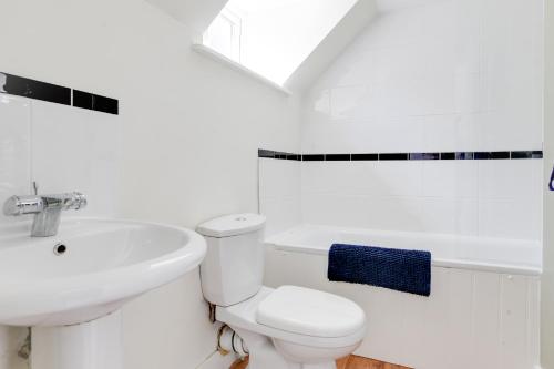a white bathroom with a toilet and a sink at Cosy 3 bedroom house with Free parking and WiFi in Colchester