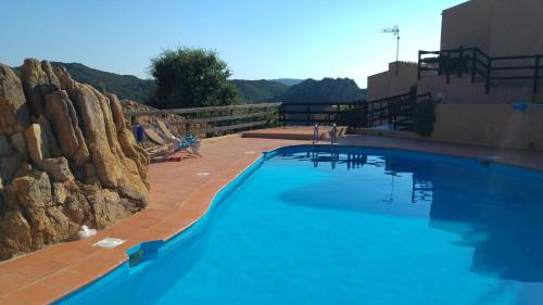 Una gran piscina azul con un muro de piedra. en Angolo di Paradiso, en Costa Paradiso