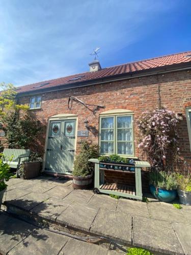 a brick house with a bench and a blue door at Beech Farm cottages in Tetney