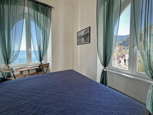 a bedroom with a blue bed and large windows at Hotel Meublè Agavi in Monterosso al Mare