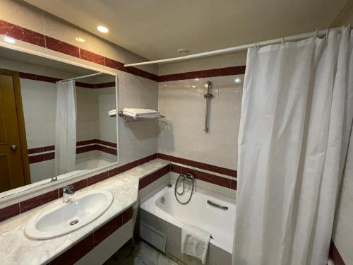 a bathroom with a sink and a tub and a shower curtain at Marina Palace in Hammamet