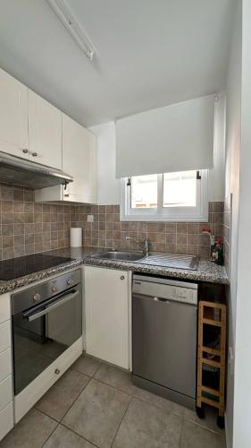 a kitchen with white cabinets and a sink at D1PeyiaGarden in Peyia
