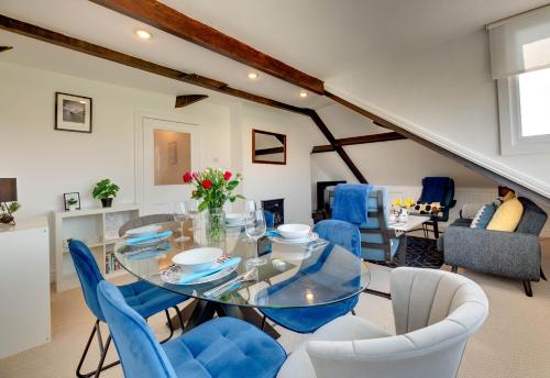 a dining room with a glass table and blue chairs at Percy Apartments - By Week2Week in Tynemouth