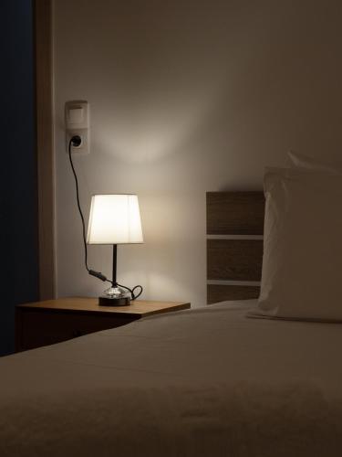 a lamp sitting on a table next to a bed at Natalia's Lovely House in Artemida