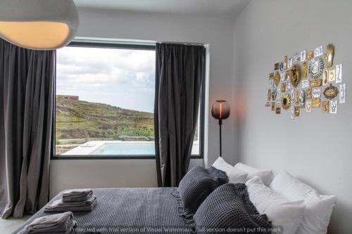 a bedroom with a bed and a large window at Rockaine Suites Eclipse in Tinos