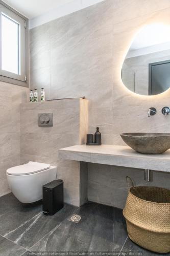 a bathroom with a sink and a toilet and a mirror at Rockaine Suites Eclipse in Tinos