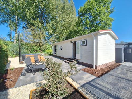 a small white tiny house with a patio at Stelle Maris Wellness, carefree enjoyment! Private Sauna & Hottub in Zeeland, Airco, Free Wifi and more! in Heinkensand