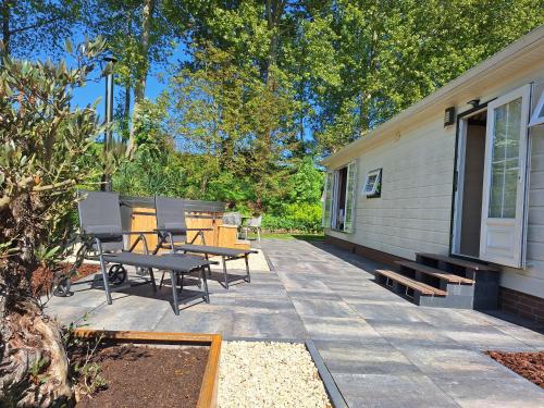 a patio with a table and benches next to a house at Stelle Maris Wellness, carefree enjoyment! Private Sauna & Hottub in Zeeland, Airco, Free Wifi and more! in Heinkensand