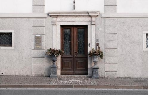 a brown door on a white building with two vases at La Cles Deluxe Suites in Cles