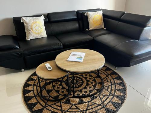 a black couch with two tables in a living room at The little Heaven in Baie Nettle