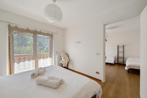 a white bedroom with a bed and a window at Le Nene - Dolomiti guesthouse in Pieve di Cadore