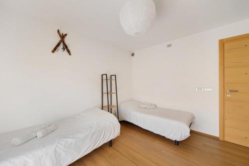 two beds in a room with white walls and wooden floors at Le Nene - Dolomiti guesthouse in Pieve di Cadore