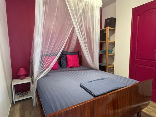 ein Schlafzimmer mit einem Bett mit Baldachin und rosa Wänden in der Unterkunft Paradis Tropical in Grande Anse
