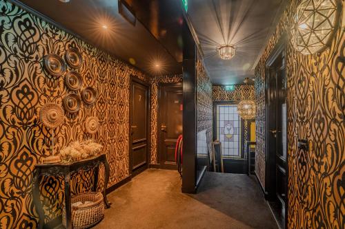 a hallway with ornate wallpaper and a table in a room at Boutique Pension Code Rosé in Noordwijk