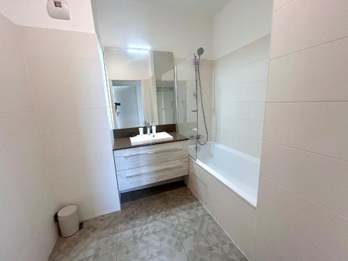 une salle de bain avec un lavabo, une baignoire et un miroir dans l'établissement L'appartement des Batignolles, à Paris