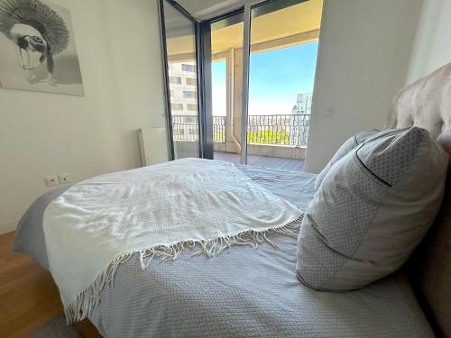 Cette chambre comprend un lit blanc et une grande fenêtre. dans l'établissement L'appartement des Batignolles, à Paris