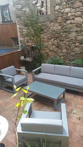 a patio with couches and tables and a stone wall at Les deux arches in Caunes-Minervois