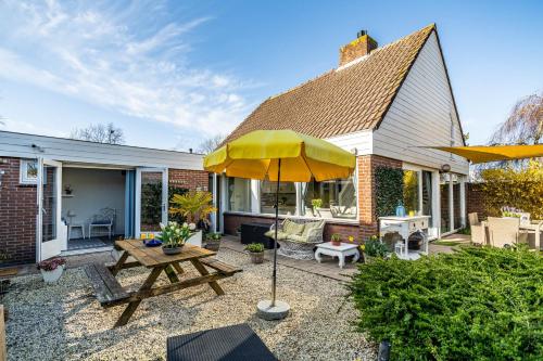 a patio with a wooden table and an umbrella at Huisje Bloemenzee in Noordwijkerhout