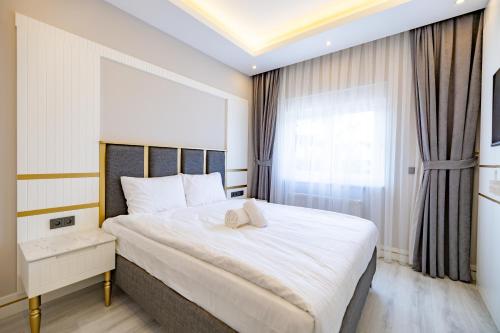 a bedroom with a large white bed and a window at Granada New Life Residence and Villas in Belek