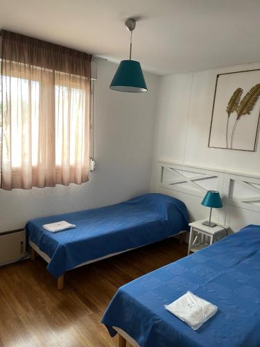 - 2 lits dans une chambre avec des draps bleus dans l'établissement Patrimoine et immobilier Villas du Lac, à Soustons