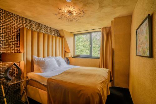 a bedroom with a bed and a window and a chandelier at Boutique Pension Code Rosé in Noordwijk
