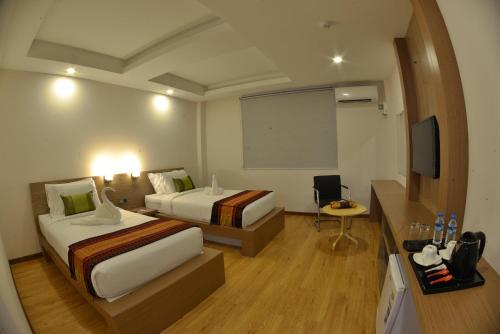 a hotel room with two beds and a projection screen at Serene Valley Hotel in Yangon