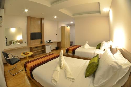 a hotel room with two beds and a television at Serene Valley Hotel in Yangon