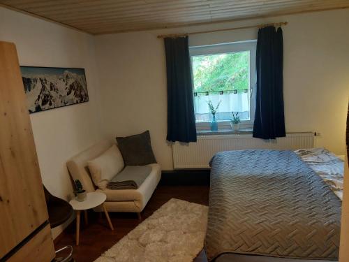 a bedroom with a bed and a couch and a window at Huber's Lodge in Hainzenberg