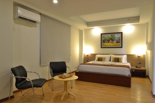 a bedroom with a bed and a table and chairs at Serene Valley Hotel in Yangon