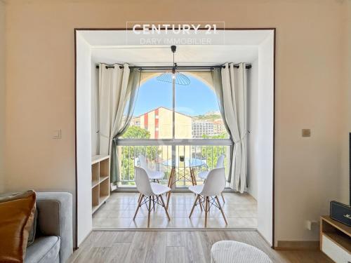 - un salon avec une table, des chaises et une grande fenêtre dans l'établissement Duplex T2 - Madonna di a Sarra, à Calvi