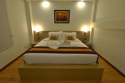 a large bed in a room with two lights at Serene Valley Hotel in Yangon
