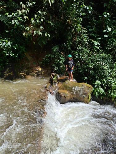 a man standing on a rock in a river at Glamping Montaña de Sueños in Cali