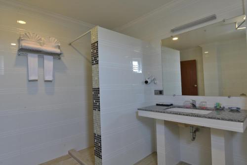 a white bathroom with a sink and a mirror at Serene Valley Hotel in Yangon