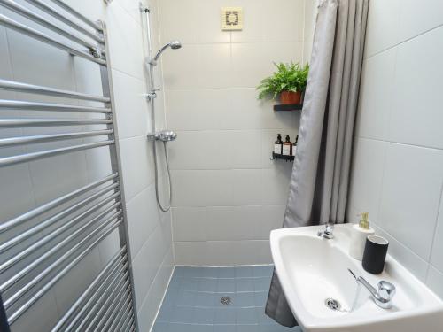 a white bathroom with a sink and a shower at Middle Cottage in Louth