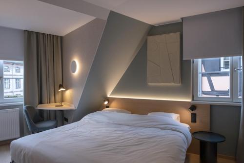 une chambre avec un lit blanc et une fenêtre dans l'établissement Logis Hôtel Restaurant Au Cerf d'Or, à Strasbourg