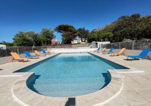 une piscine avec des chaises longues bleues et une piscine dans l'établissement Les Cariatides, à La Cotinière