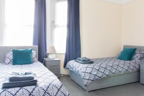 a bedroom with two beds with blue curtains and a window at Thornbury Guest House Room 5 in Southampton