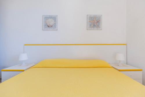 - une chambre avec un lit jaune et deux lampes dans l'établissement Casa Vista Darsena - HelloElba, à Portoferraio
