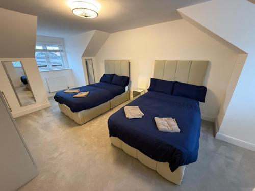 a bedroom with two beds with blue comforters at Cheshire home by Chelsea in Macclesfield