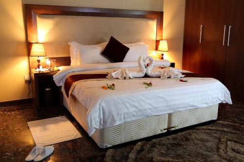 a hotel room with a bed with two towels on it at Belle Tower Apartments in Manama