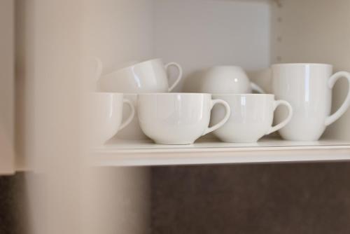 a shelf with white cups and vases on it at Residence Walchhof in Schenna