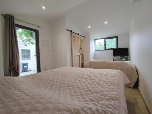 a white bedroom with a bed and a window at La croisée des destins in Viviers