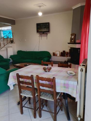 a living room with a table with chairs and a green couch at family in Kardítsa
