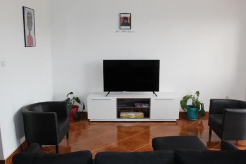 a living room with a flat screen tv and chairs at La Kaza du Soleil in Tarrafal